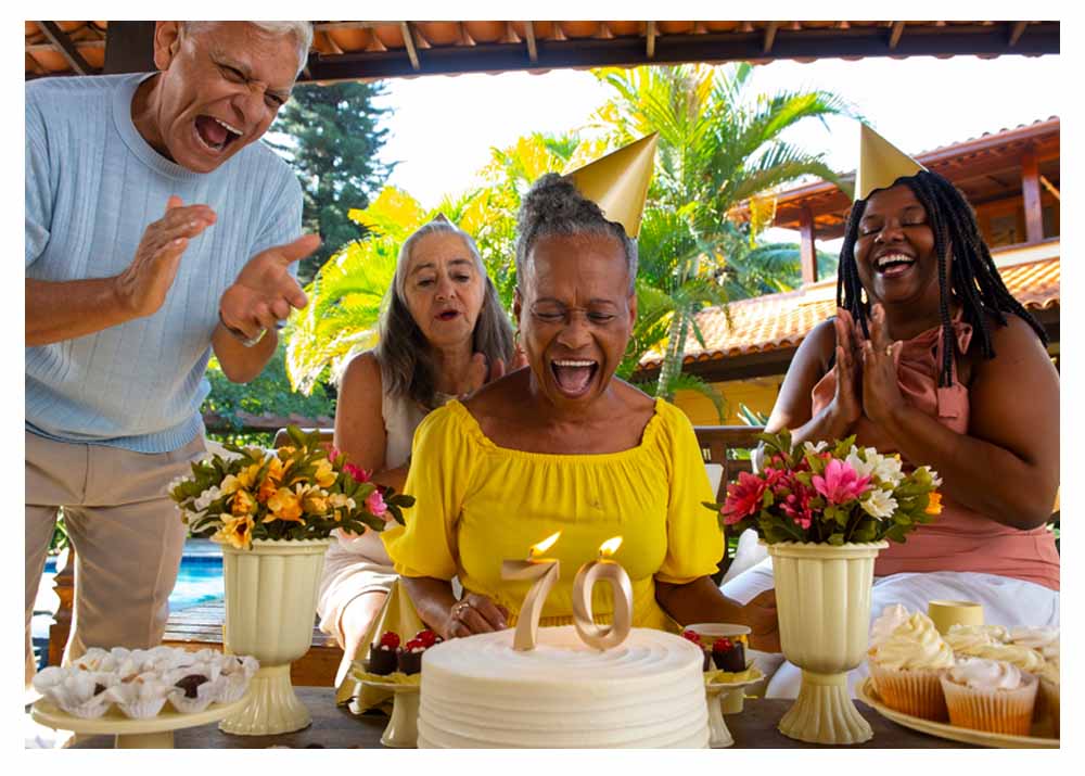 Family celebrating a 70th birthday milestone with cake and candles in a private destination setting.